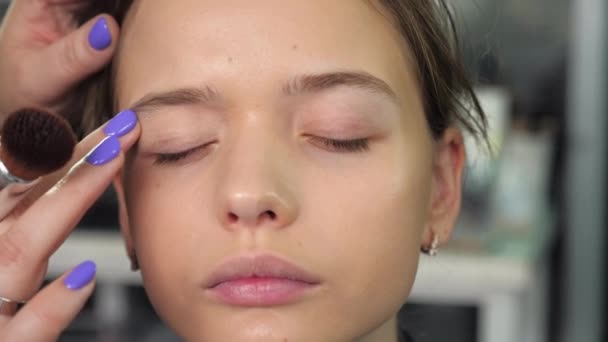Makijaż artysta stosuje krem na twarz z palcami dziewczyny w salonie — Wideo stockowe