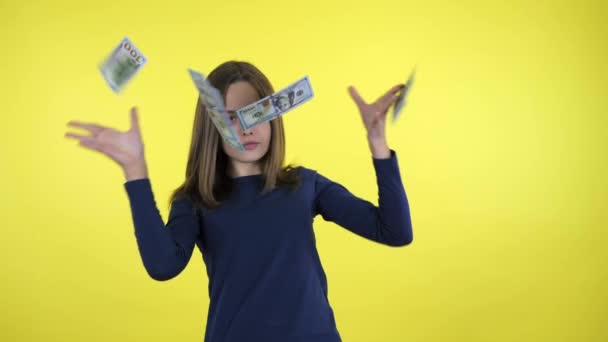 Bohaté teenager dívka v modrém svetru rozptyluje peníze na žlutém pozadí — Stock video