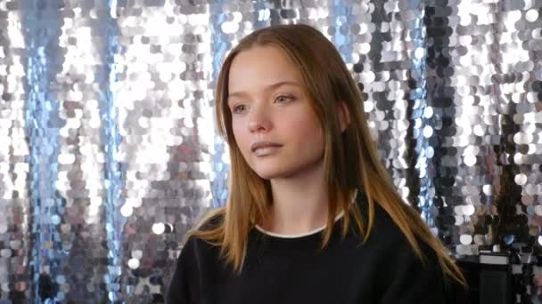 Подросток с красивым макияжем на блестящем серебряном фоне в салоне красоты — стоковое видео