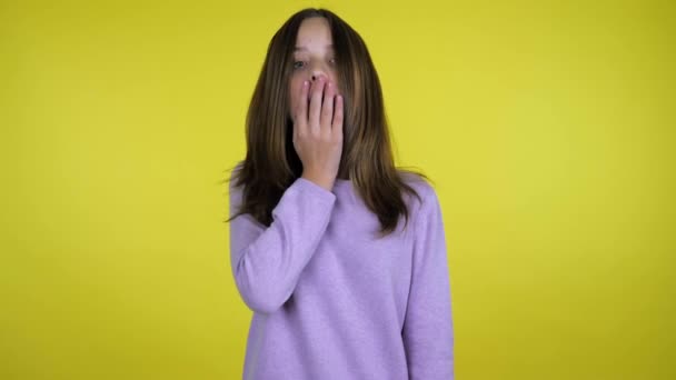 Tiener meisje in een roze trui verhoogt haar hoofd en is geschokt, zet hand in mond — Stockvideo