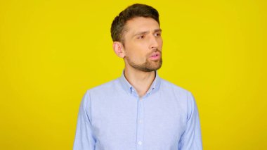 Yakışıklı sakallı adam, sarı arka planda kopyalanmış bir yere bakıyor.