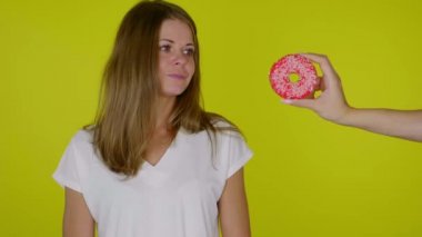 Diyet yapan aç bir kadın donut yemek istiyor ama işe yaramıyor, üzgün.