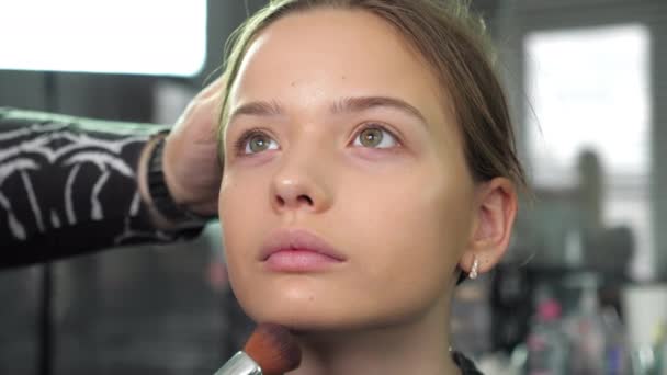 化妆师在沙龙里用刷子把粉底涂在少女脸上 — 图库视频影像