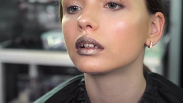 Make-up malíř aplikuje rtěnku na rty pomocí štětce na dospívající dívku v salonu — Stock video