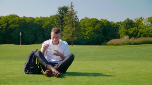 Människan äter sin vegetariska lunch med ett ekologiskt paket, visar ett liknande och leenden — Stockvideo
