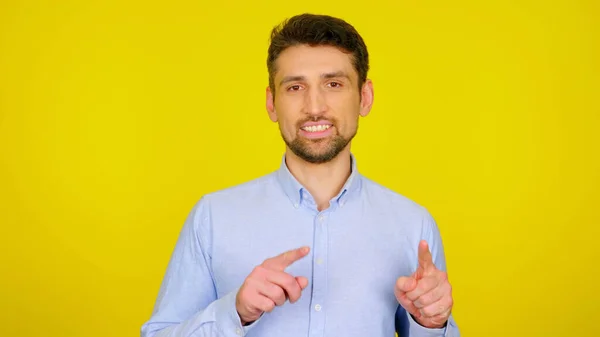 Bonito barbudo homem em uma camisa azul clara sorri e mostra seus dedos — Fotografia de Stock