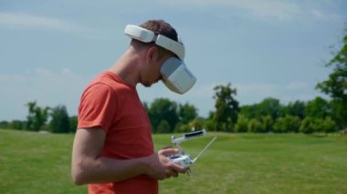 Adam bir kuadrokopteri uzaktan kumandayla kontrol ediyor.