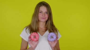 Beyaz tişörtlü kadın mavi ve kırmızı çöreklerle el kaldırıyor, gülümsüyor.