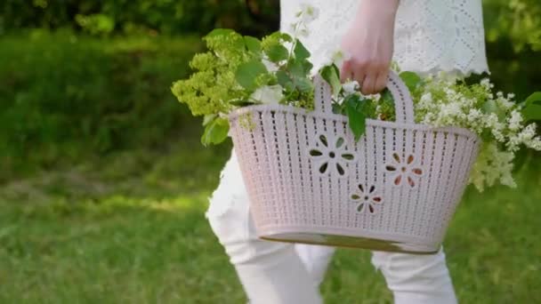 Femme porte un panier avec des fleurs à la main. Maman, fils dans la main, marche — Video