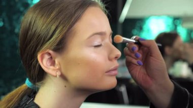 Makyöz, güzellik salonundaki genç bir kıza göz farı sürüyor.