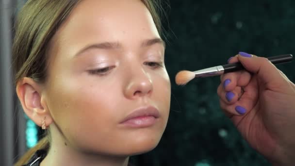 Maquiagem artista aplica pó no rosto com escova para menina adolescente no salão — Vídeo de Stock