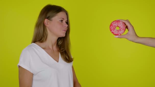 Mulher em uma dieta em uma camiseta branca recusa um donut saboroso doce — Vídeo de Stock