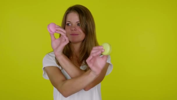 Femme dans un T-shirt blanc danse avec des macarons roses et jaunes dans les mains — Video