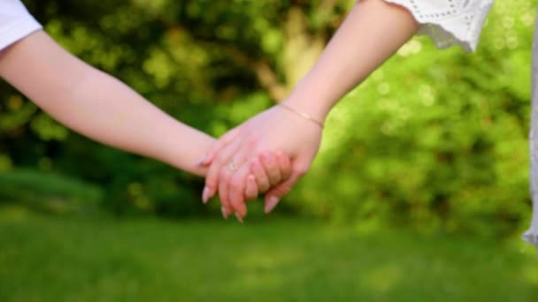 Zavřít maminka a syn držet za ruce, procházka podél trávy v botanické zahradě — Stock video