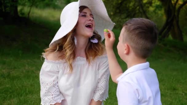 Sonen stoppar gröna druvor i munnen, kvinnan tuggar, äter och njuter av smaken — Stockvideo