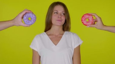 Aç kadın etrafına bakar, ısırır ve dudaklarını yalar ve hangi çöreği yiyeceğini seçer.