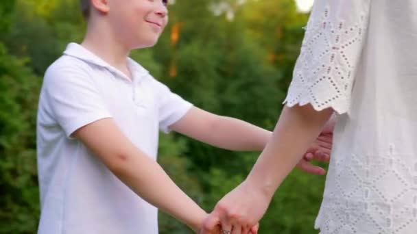Close up happy mom and son hold hands, spin, smile. Woman, little boy play park — Stock Video