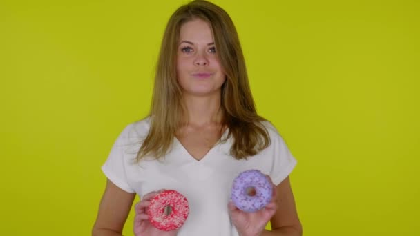 Vrouw in een wit T-shirt draait blauwe en rode donuts op de borst en glimlacht — Stockvideo