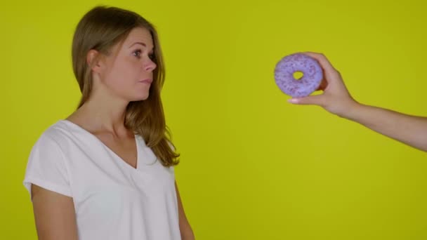 Vrouw op dieet in een wit T-shirt weigert een zoete lekkere donut — Stockvideo