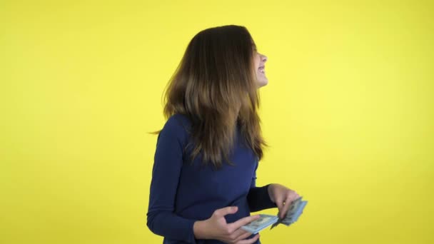 Bohaté dospívající dívka smích s penězi v rukou na žlutém pozadí — Stock video