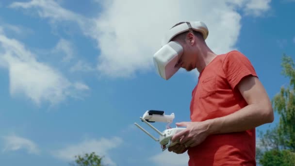 De man bestuurt een quadrocopter via een afstandsbediening. Blauwe lucht op de achtergrond — Stockvideo