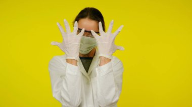 Koruyucu tıp maskeli, gözlüklü ve lateks eldivenli genç doktor.