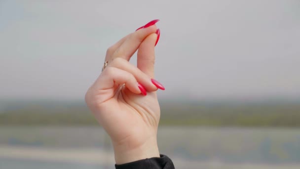 Close-up vrouw hand met rode nagellak knipt vingers buiten — Stockvideo