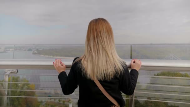 Voltar mulher vista na ponte de vidro, olha para belas árvores paisagem floresta rio — Vídeo de Stock