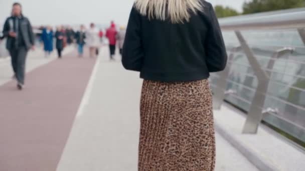 Back view blonde woman walks on pedestrian bridge, looks around outdoors — Stock Video