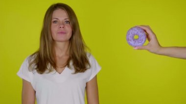 Beyaz tişörtlü, diyet yapan aç bir kadın donutu ısırmak istiyor ama işe yaramıyor.