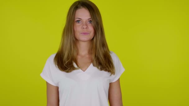 Vrouw in een wit T-shirt kijkt naar de camera, steekt de hand op met een donuts — Stockvideo