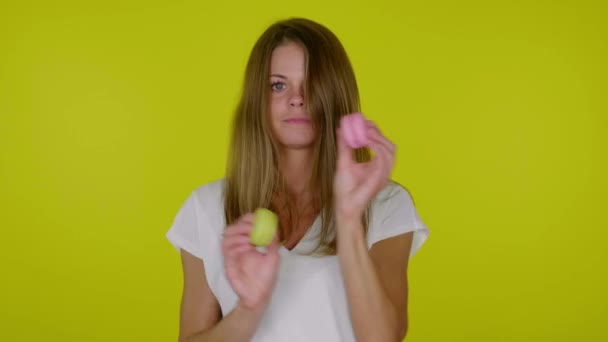 Donna in t-shirt bianca balla con macaron rosa e gialli in mano — Video Stock