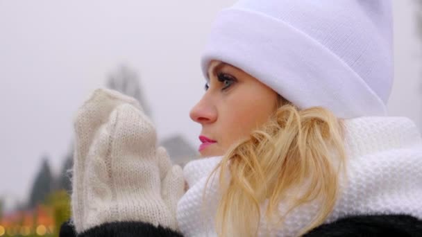 Chiudi donna congelato in cappello bianco, sciarpa, guanti riscalda le mani, palme sfregamento — Video Stock