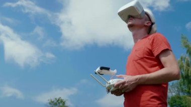 Adam bir kuadrokopteri uzaktan kumandayla kontrol ediyor.