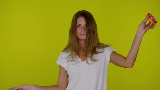 Femme drôle dans un T-shirt blanc danse avec des beignets rouges et bleus dans les mains — Video