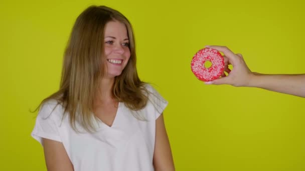 Mulher em uma dieta olha para o donut, sorri, lambe e morde lábios, quer comer — Vídeo de Stock