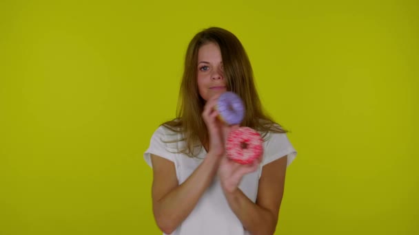 Mulher de t-shirt branca dançando com rosquinhas vermelhas, azuis nas mãos, sorrindo — Vídeo de Stock