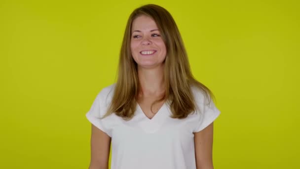 Frau im weißen T-Shirt lacht auf gelbem Hintergrund mit Kopierraum — Stockvideo