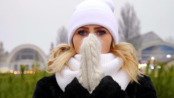 Close up frozen woman in white hat, scarf, mittens warms hands, rubbing palms — Stock Video