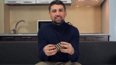 Mutlu yakışıklı adam çizgili kutuyu yakalıyor, gülümsüyor, kamera gösteriyor.