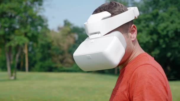 Man in een virtual reality helm draait zijn hoofd naar links en naar beneden — Stockvideo