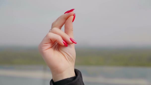 Close up mão mulher com esmalte de unhas vermelhas ao ar livre . — Vídeo de Stock