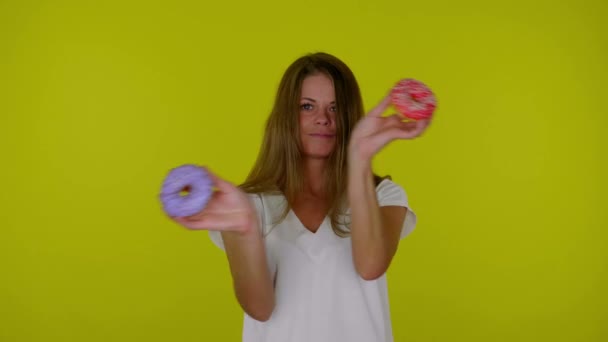 Lustige Frau im weißen T-Shirt tanzt mit roten und blauen Donuts in der Hand — Stockvideo