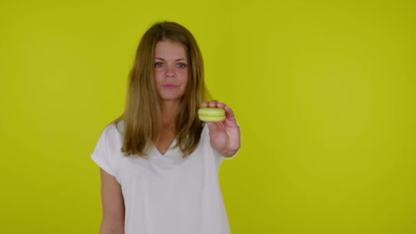 Donna alza la mano con un macaron giallo nella fotocamera e sorride — Video Stock