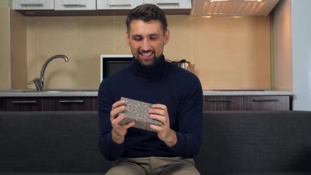 Happy handsome man catches box in snowflakes, examines, smiles, rejoices gift — Stock Video