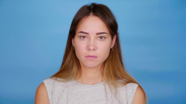 Mujer culpable en camiseta gris asiente con la cabeza y dice que sí sobre fondo azul — Vídeos de Stock