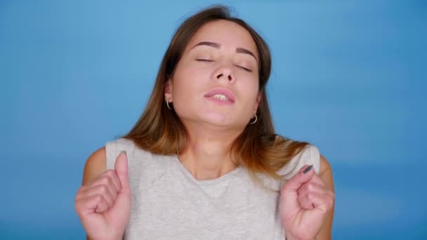 Femme fatiguée en t-shirt gris bâillements, s'étend sur fond bleu avec espace de copie — Video