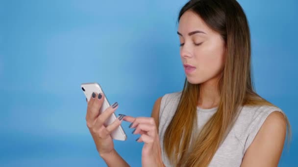 Donna in t-shirt grigia utilizza smartphone, sorpreso dei prezzi nel negozio online — Video Stock