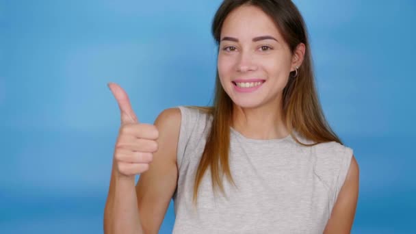 Mooie positieve vrouw in grijs t-shirt tonen duim omhoog, willen en glimlachen — Stockvideo