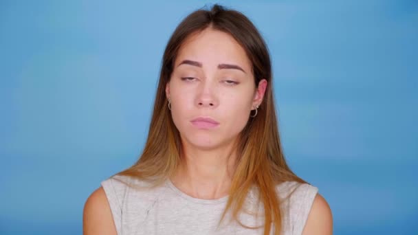 Kvinna i grå t-shirt nickar huvud och säger nej på blå bakgrund med kopia utrymme — Stockvideo